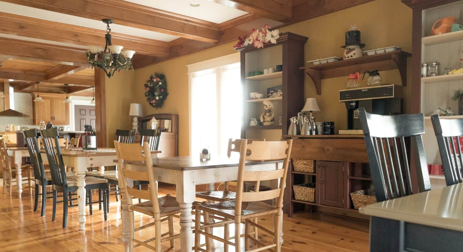 Elegant and rustic dining area off of a kitchen with coffee hutch and several tables with chairs