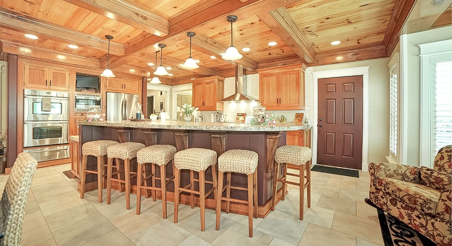 Expansive kitchen with large island and stools, pendant lighting and stainless steel appliances