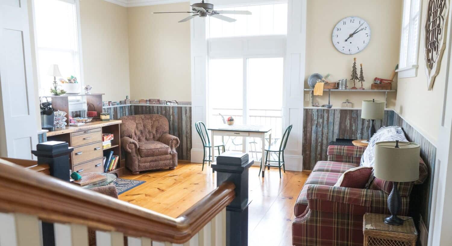 Living room area with couch, two chairs, dresser with games and sliding glass doors onto an outside patio