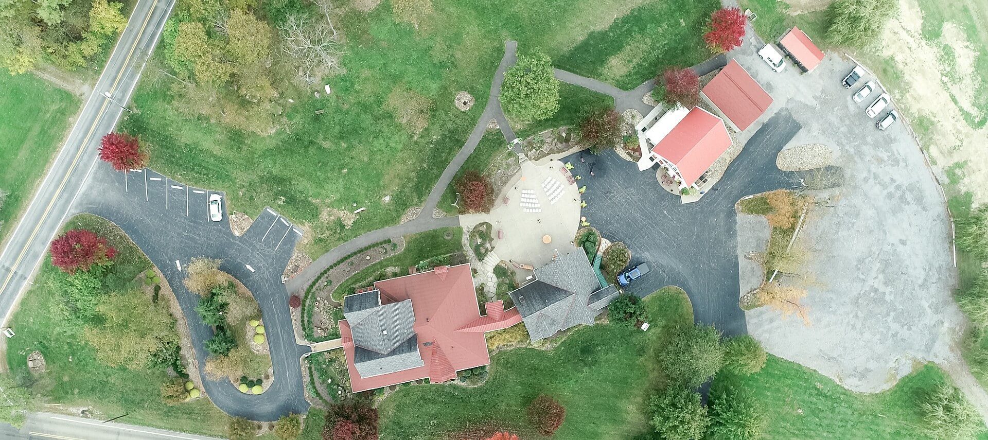 Overhead aerial image of home with multiple outbuildings, two parking lots and expansive lawn areas